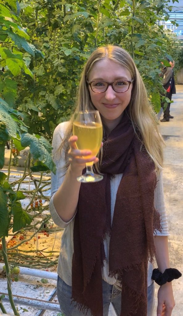 Amanda toasting with a tomato beer inside Fridheimar's Greenhouse